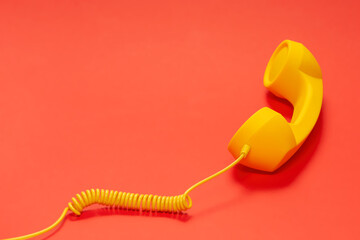 Yellow handset on red background. Copy space.