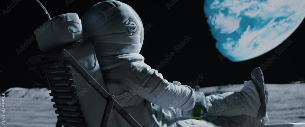 Wall mural back view of lunar astronaut opens a beer bottle while resting in a beach chair on moon surface, enj