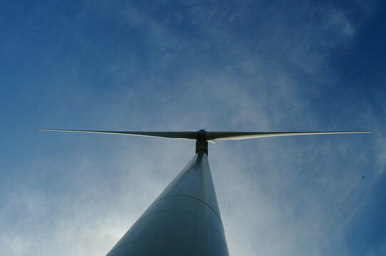 Silhouette of a wind turbine against a blue sky.