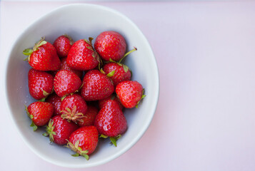 Top view shot of delicious fresh strawberries in a bowl on pastel background, copy space