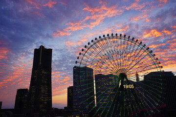 Cityscape of Yokohama Minatomirai at sunset in Japan. Ferris wheel at Cosmo World - 日本 神奈川県 横浜 みなとみらい 観覧車 夕日