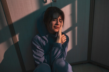 Woman sitting on the floor in the dark with smeared make up after crying