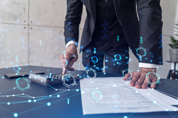 A research and development specialist computing the data to create a new approach to develop high tech business. Technological icons over the desk with calculator.