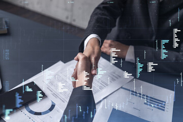 A handshake symbolize a capital market transaction to proceed profit in stock trading. Financial hologram chart over the table with the document. Women in business concept.