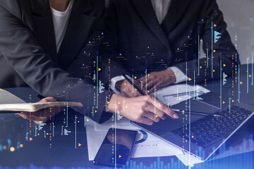 Two traders researching historic data to predict stock market behavior. Women in trading business concept. Forex and financial hologram chart over the table with the document.