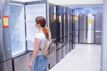Caucasian woman chooses a refrigerator in a home appliance store