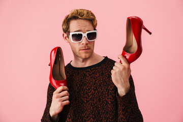 Stylish young white man gay showing high heel red shoes