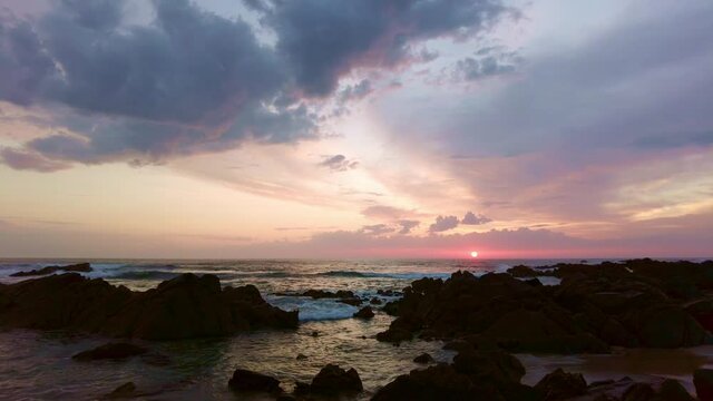 Sunset ocean.Calm sea waves on stones. Water splash. Colorful sky. Sea landscape. Romantic vacation. Portugal. Afife