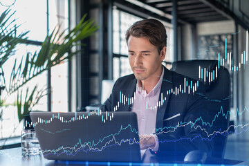 Handsome businessman in suit at workplace working with laptop to optimize trading strategy at corporate finance fund. Forex chart hologram over office background - obrazy, fototapety, plakaty
