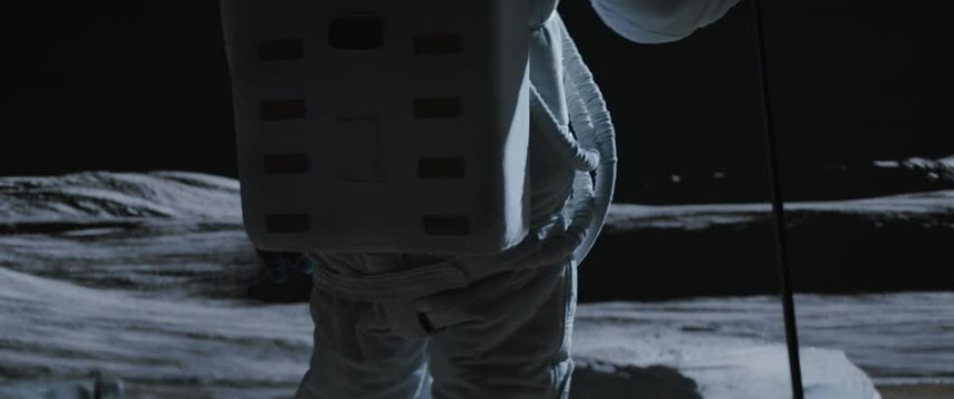 Portrait of Asian lunar astronaut placing a flag pole on the Moon surface. Easy to track and add your flag. Shot with 2x anamorphic lens