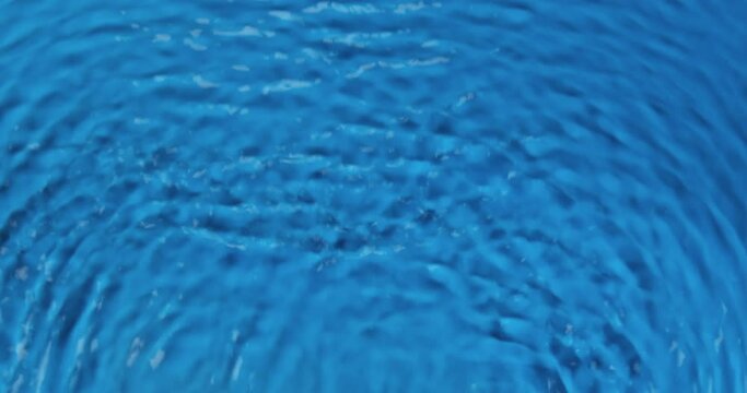 Waves in blue water, wavy movement of water. Vertical motion. Ripple lines. Top view. Water texture.