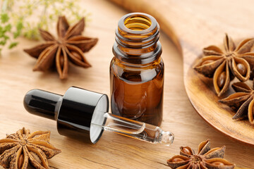 Star anise essential oil on bottle on wooden table. Alternative medicine - obrazy, fototapety, plakaty
