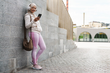 Middle eastern woman in hijab using mobile phone while standing outdoors