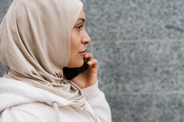 Middle eastern woman in hijab talking on cellphone outdoors