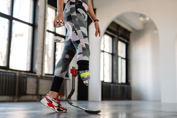 Obraz premium Young sportswoman with prosthesis holding headphones while working out