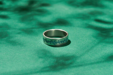 Creative silver ring with embossing on green background