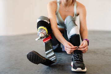 Young sportswoman with prosthesis tying her shoelaces