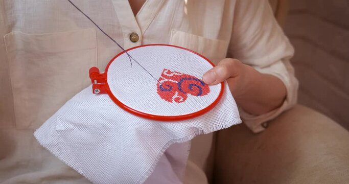 Woman do needlework. A woman has a hobby and do a needlework in the armchair in the room.