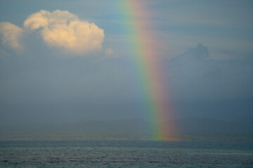 Rainbow over cloudy sky with sea and mountain land