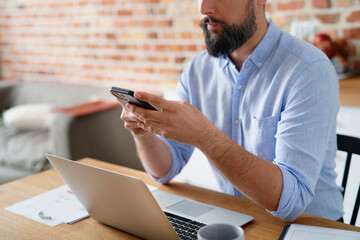 Close up of man holding phone during home office