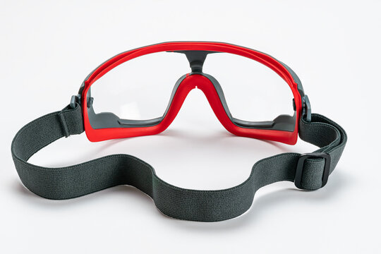 Back view of red and gray frame of multipurpose goggles with black elastic strap on white background.