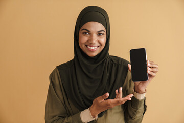 Black muslim woman in hijab smiling and showing mobile phone