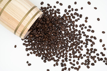 Lots of fresh brown coffee beans spilled out of oak barrel on the white background.
