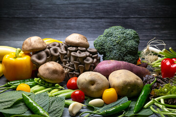Various fresh vegetables in front of the dark wood pattern background.