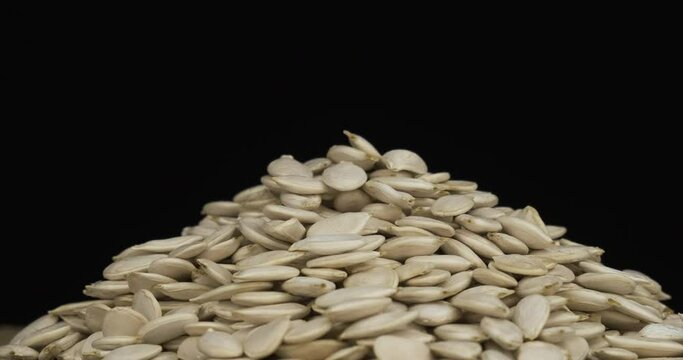 Close-up. Rotation of a heap of pumpkins grains. Isolated on black background.