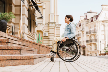 Brunette woman sitting in wheelchair by stairs on city street