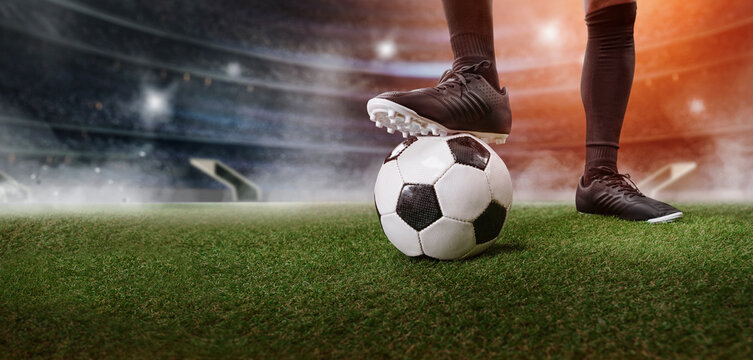 Feet of soccer player step on soccer ball for kick off in stadium