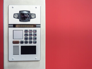 Video intercom on background of red wall. Modern intercom with video camera. Concept - equipment...