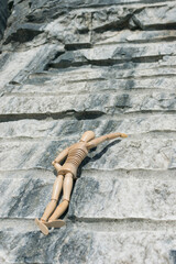 Wooden man climbing a rock outdoors.
