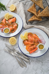 Gravlax Graved Lachs Asiaitsche Art und Klassisch, ein roh gebeizter Fisch mit Zitronengras, Chili, Dill, Hovmästarsås Senf Soße, Toast, Zwiebel Ringe und Zitrone auf Emaille Teller und Leinen Tuch au