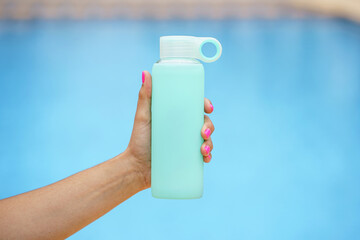 horizontal view of unrecognizable woman grabbing a bottle of cold water. Hydration and fitness lifestyle. Exercise and healthy sport habits in summer.