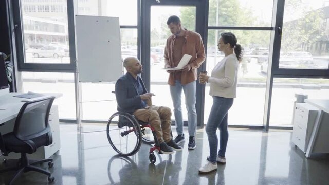 man holding folder with charts near handicapped african american boss and woman