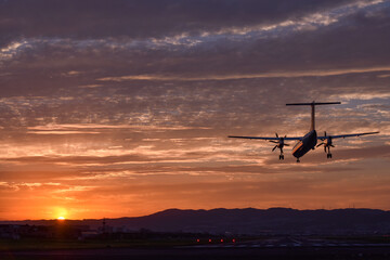 美しい夕焼けに着陸する飛行機