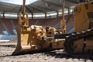  A bulldozer removes turf on a soccer field. - obrazy, fototapety, plakaty