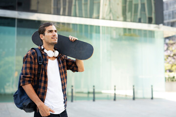 Portrait of handsome man with skateboard. Young stylish man with skateboard outdoors.