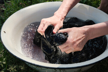 Young girl washes clothes by hand in basin.