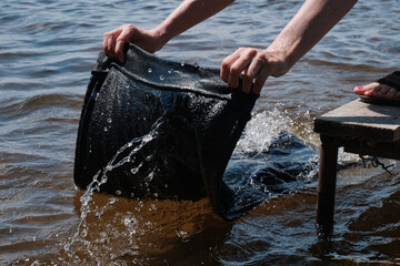 Young girl washes clothes by hand in lake.