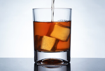 glasses of whiskey with ice cubes on black glass surface	