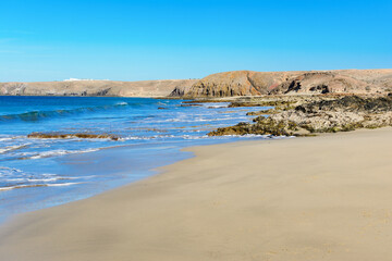 View of beautiful Papagayo beach near town named Playa Blanca, Lanzarote, Canary Islands. View of blue sea, yellow sand, selective focus