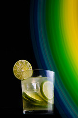 .Brazilian cocktail called Caipirinha. With lemon, ice and cachaça on a dark background with colored lights. Copy space