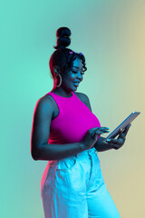 Young beautiful happy African girl isolated on blue-green background in neon.