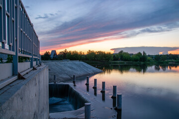 lake with waterfall at sunset with vanilla clouds on a summer evening