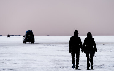 Young couple on their backs walk through the apocalyptic landscape of the Salt Flats , with...
