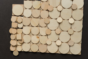 tiled background composed of thin, untreated or natural wooden shapes - loosely arranged on a dark gray ground - photographed in a top-down style 