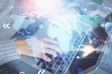 Double exposure of woman hands working on computer and world map hologram drawing. International technology business concept.
