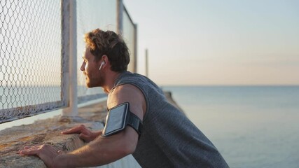 Young strong sporty athletic toned fit sportsman man in sports clothes earphones warm up training doing push-ups clap at sunrise sun dawn over sea beach outdoor on concrete pier seaside in summer day